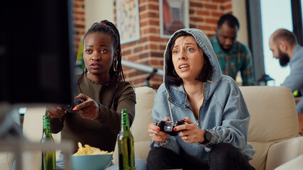 Excited group of friends celebrating video games win, feeling happy about winning online competition with tv gaming console. Cheerful women playing challenge on television. Handheld shot.