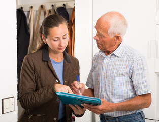 Elderly man signing financial agreement with bank worker at home