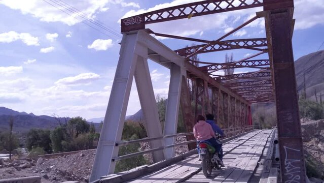 Local People on Motorcycle Crossing an Old Steel Bridge near the Pukara of Tilcara, Jujuy province, Argentina.  