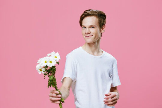 a cute, friendly guy stands with chamomile flowers in a ruach, holding them out to the camera