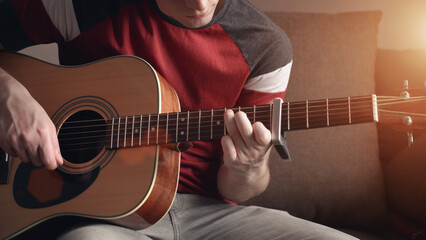 Cheerful young man is learning to play the acoustic guitar. remote online lesson.