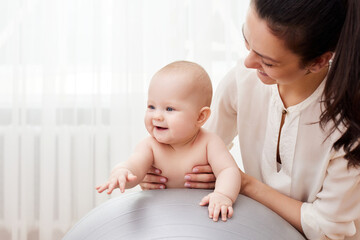 mother playing with her baby girl on a fitness ball