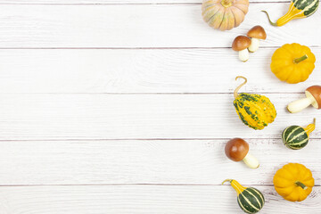 Fall flat lay with colorful pumpkins and mushrooms on white wooden background. Autumn border mockup with decoration. Top view. Copy space.