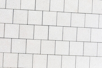 Obraz premium Coating with modern textured paving tiles of square shape. White square paving slabs interspersed with natural stone. Sample of material for paving garden path, sidewalk, square. copy space