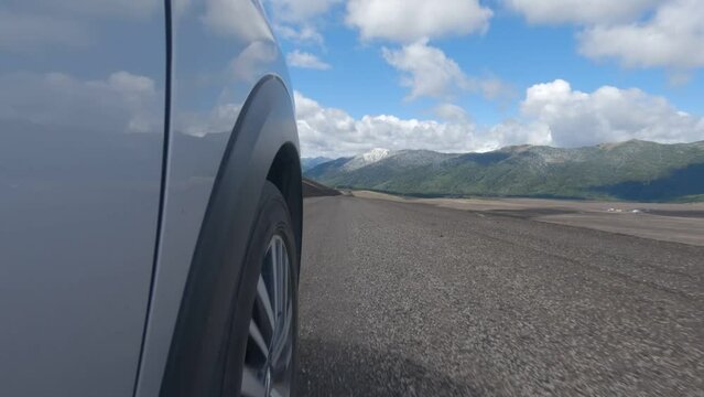  Vista a nivel del suelo de c&aacute;mara de acci&oacute;n. Camioneta recorriendo viajando un camino de ripio, cielo azul y nubes en el sur de chile.