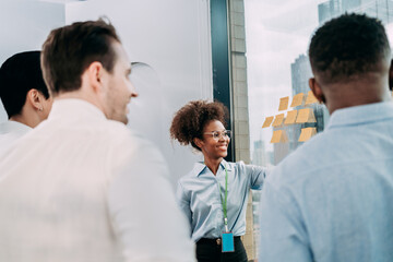 Fototapeta premium Groups of business people diverse brainstorming presentation ideas using label color sticky on glass wall together in the office, planning strategy new marketing projects, and teamwork concepts.