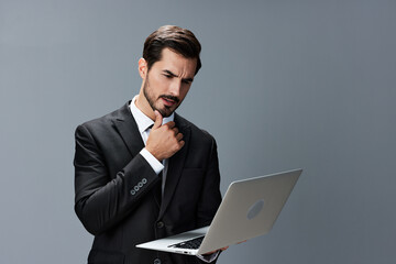 Man business tired stressed out looking at his laptop and working online via internet in business suit video call business talks on gray background copy place