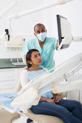 Obraz premium Dentist showing X-ray to patient in clinic