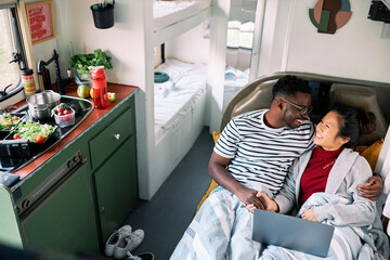Multiracial pair cuddles in their home on wheels.