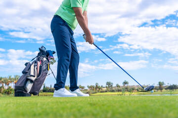 Man playing golf at golf club by a lake, preparing to hit