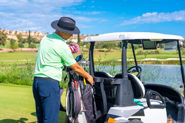 Man playing golf, picking up the club after the release in the club bag and placing it in the buggy