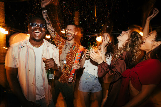 A Group of people has a great time at the rooftop nightclub and throws confetti.