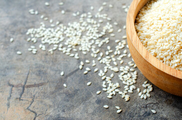 Close up of white sesame seeds in wooden bowl for raw food backgrounds