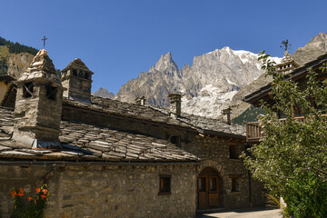 The alpine village with the Aiguille Noire de Peuterey peak of the Mont Blanc Massif in the background in summer, Entreves, Courmayeur, Aosta Valley, Italy