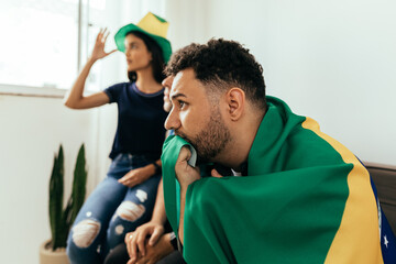 Nervous and excited sports fans watching game on TV at home. Nervous friends watching football game on the sofa.