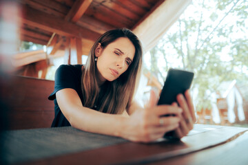 Woman Squinting Trying to Read Small Text on her Phone. Lady suffering from presbyopia aging vision problems 
