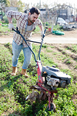 Gardener using motorized cultivator in his garden