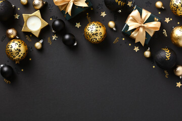 Stylish dark Christmas background with black and gold Xmas decorations, baubles, gift boxes, confetti. Flat lay, top view.