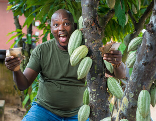 A happy African male farmer, trader, entrepreneur or businessman from Nigeria, holding and...