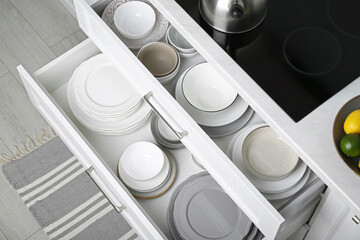 Open drawers with different plates and bowls in kitchen, above view