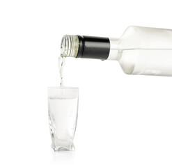 Pouring vodka from bottle in glass on white background