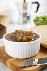 Delicious gooseberry jam and knife on white table, closeup