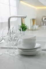 Fototapeta na wymiar Different clean dishware and glasses on countertop near sink in kitchen