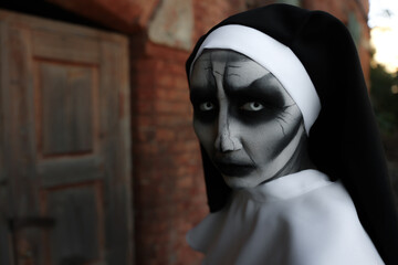 Portrait of scary devilish nun outdoors, space for text. Halloween party look