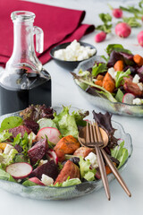 Bowls of roasted beet and carrot salad served with feta and balsamic dressing.