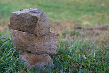 Obraz premium stacked rock column monument in an open grass field within a farm on a clear calm peaceful day on a hill in the country