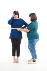 Fat Asian woman holding a tape measure around her waist to measure waist circumference of skinny...