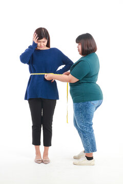 Fat Asian woman holding a tape measure around her waist to measure waist circumference of skinny women Check her waist size to help plan for weight gain or weight loss. Concept of health care.