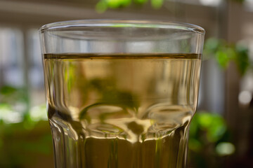 A large glass glass with green tea in a warm home environment.