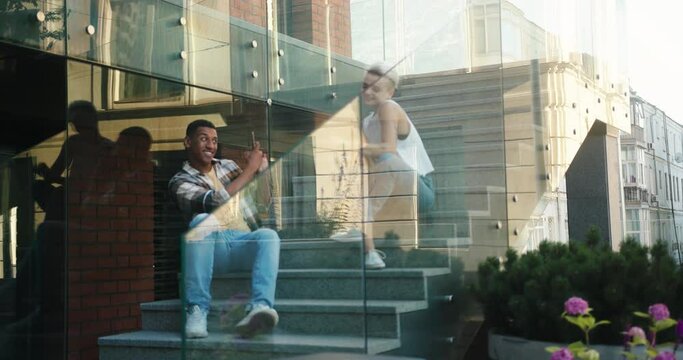 Young couple discusses fashion news leaning on glass fencing