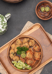 Delicious batagor or meatballs tofu is one of the popular indonesian traditional foods. Made from fish, tofu and peanut sauce. on wooden background. Top View, Close Up