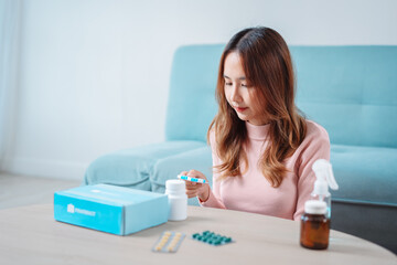 Asian young woman patient on eating table at nursing home care. Female look to medicine pills in bottle, read prescription and content. self recover health care concept.