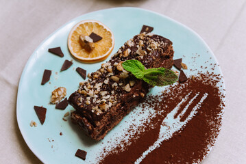 Sweet breakfast with chocolate honey biscuit cake with sour and butter cream and walnuts, a slice of dried orange and decorated with mint leaf and cocoa powder