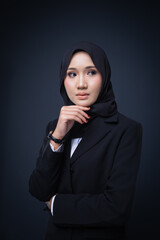 Portrait of an attractive Muslim woman wearing business attire and hijab with a corporate pose isolated on grey background. For image cut-out for technology, business or finance.