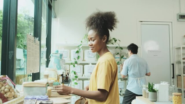Young African American woman is choosing and shopping for organic products in refill store with reusable bag, zero-waste grocery, and plastic-free, eco environment-friendly, sustainable lifestyles.