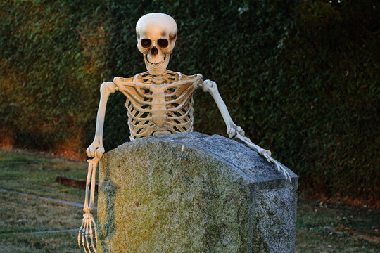 Skeleton leaning on headstone