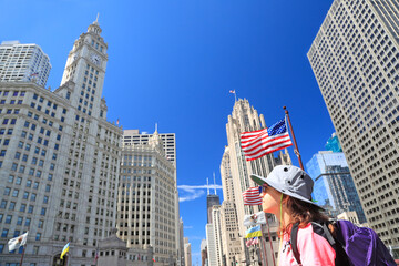 Tourist teenager admiring Chicago skyline on Michigan Avenue with American flag on the foreground...