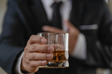 The bartender holds a glass of whiskey and ice to the male guest. The rest of the concept in the bar Close-up of serious businessman holding whiskey showing executive privilege concept.