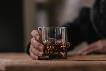 The bartender holds a glass of whiskey and ice to the male guest. The rest of the concept in the bar Close-up of serious businessman holding whiskey showing executive privilege concept.