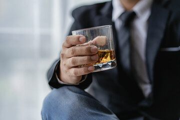 The bartender holds a glass of whiskey and ice to the male guest. The rest of the concept in the bar Close-up of serious businessman holding whiskey showing executive privilege concept.