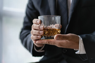 The bartender holds a glass of whiskey and ice to the male guest. The rest of the concept in the bar Close-up of serious businessman holding whiskey showing executive privilege concept.