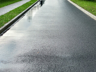 empty new asphalt road on a rainy day. wet road surface with water puddles after rain. - 534106844