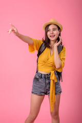 Obraz na płótnie Canvas Beautiful Asian woman traveler who enjoys relaxing summer vacation by carrying a small backpack on pink background.