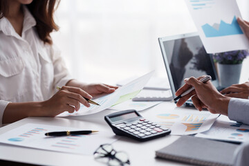 Business people point to graphs and charts on laptop to present at the meeting, analyze market data, balance sheet, net profit, to plan new sales strategies to increase productivity.