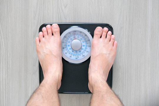 Legs of men standing on scales weight. Concept of health and weight loss.