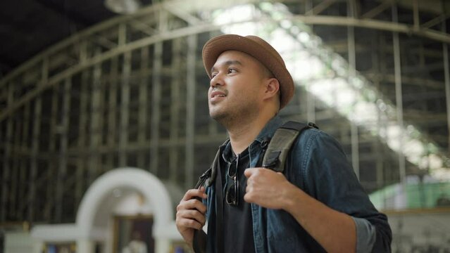 Freedom traveler young asian man at terminal train station. Happy tourist travel by train on vacation time holiday weekend trip. Male Backpacker arrival at platform railway. Go Everywhere concept.